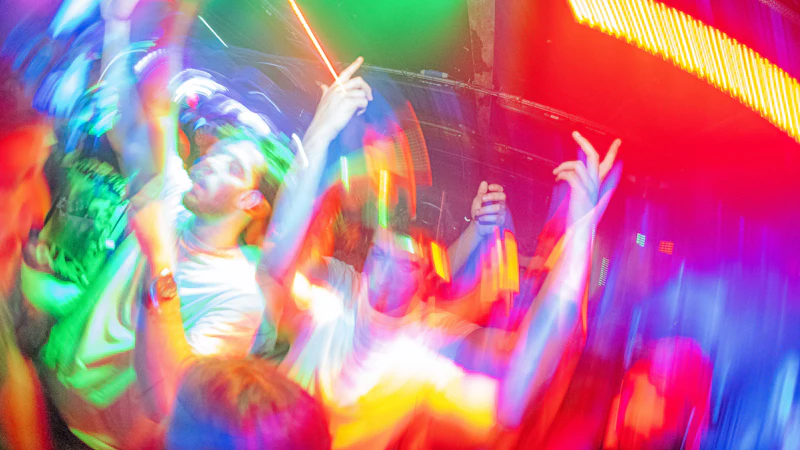 Dancers blurred by swirling colourful lights on a packed dance floor