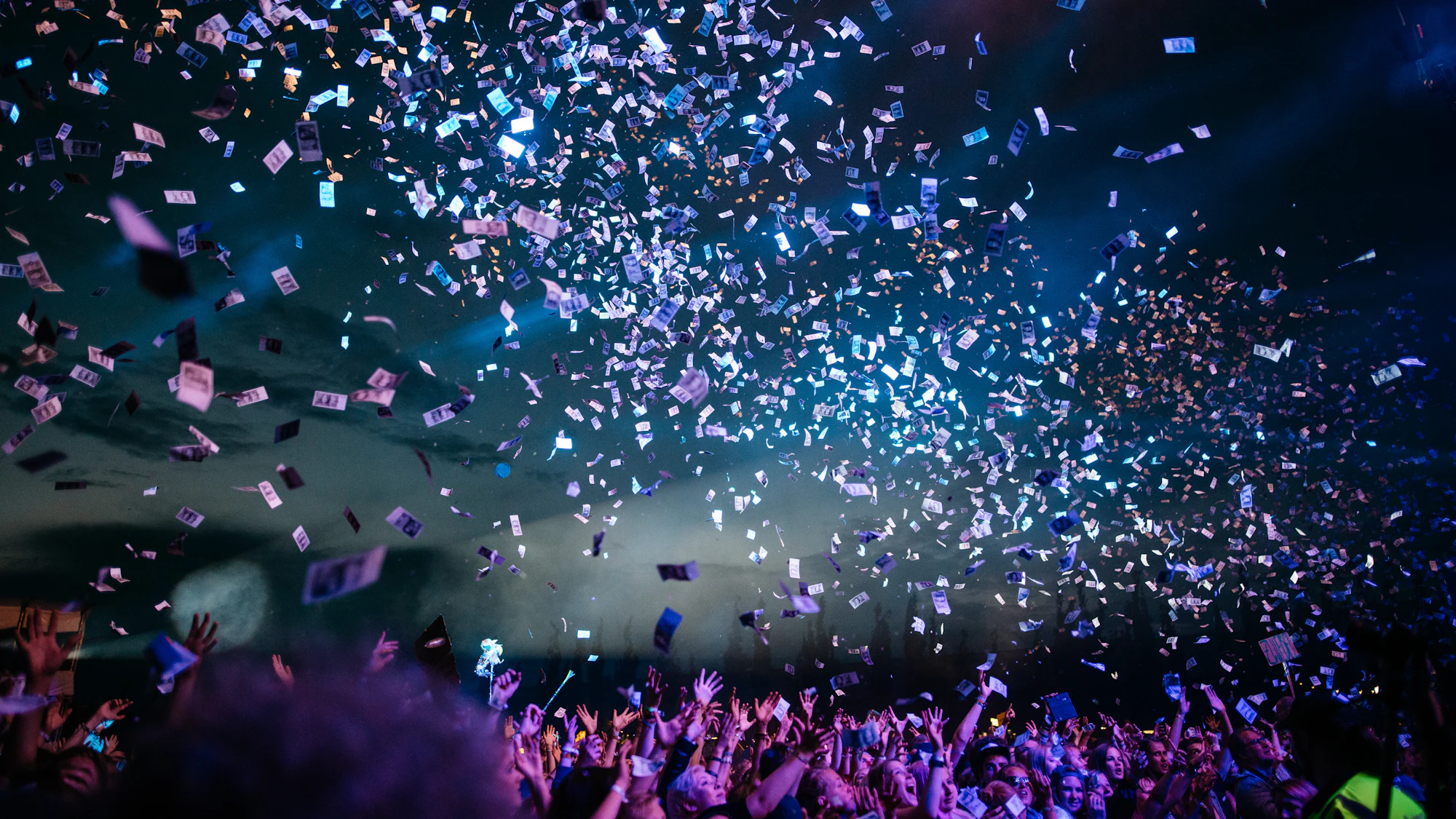 Confetti bursting over a joyful crowd with hands in the air