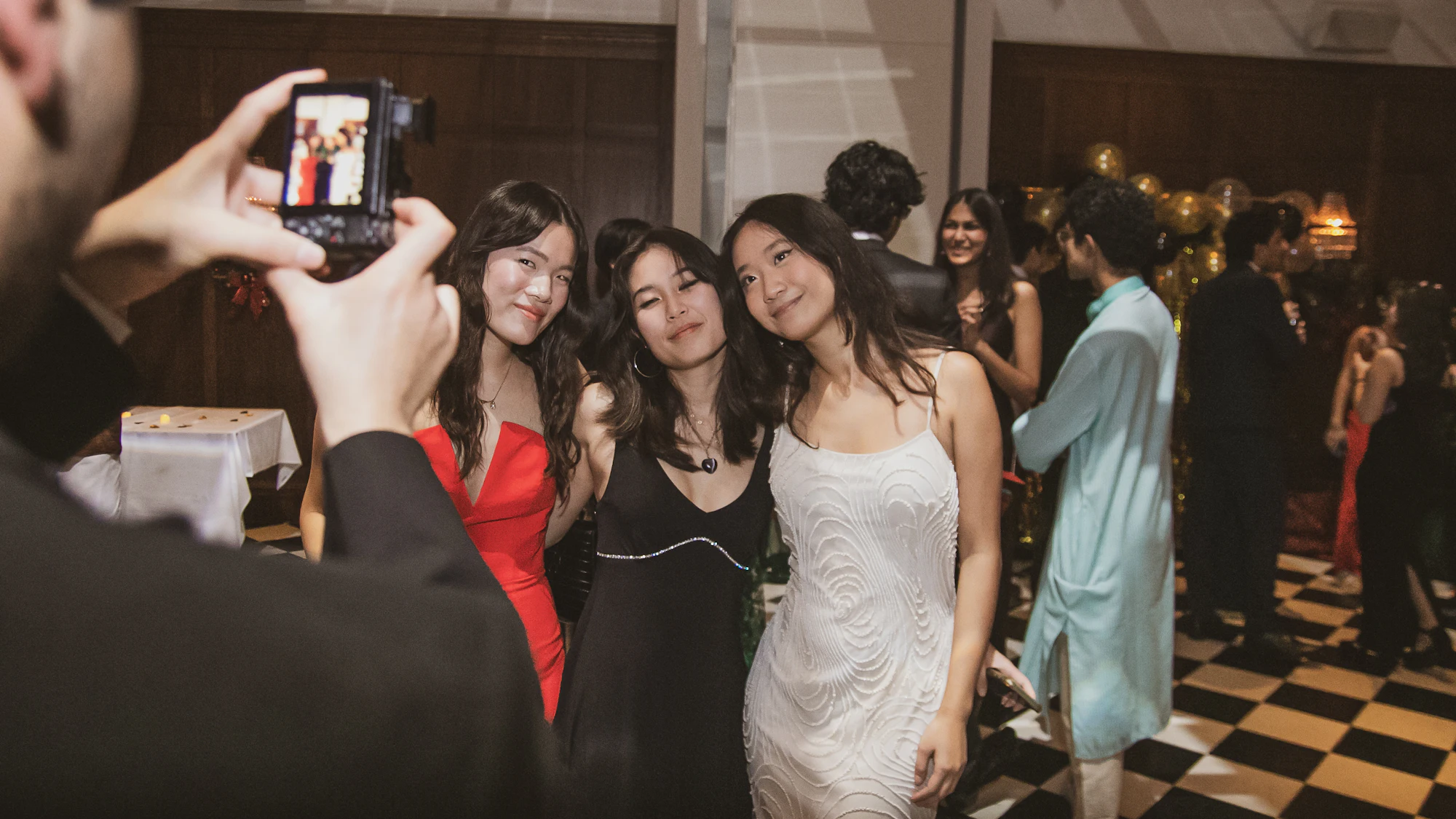 Glamorous guests in evening wear posing for photos at a black-tie party