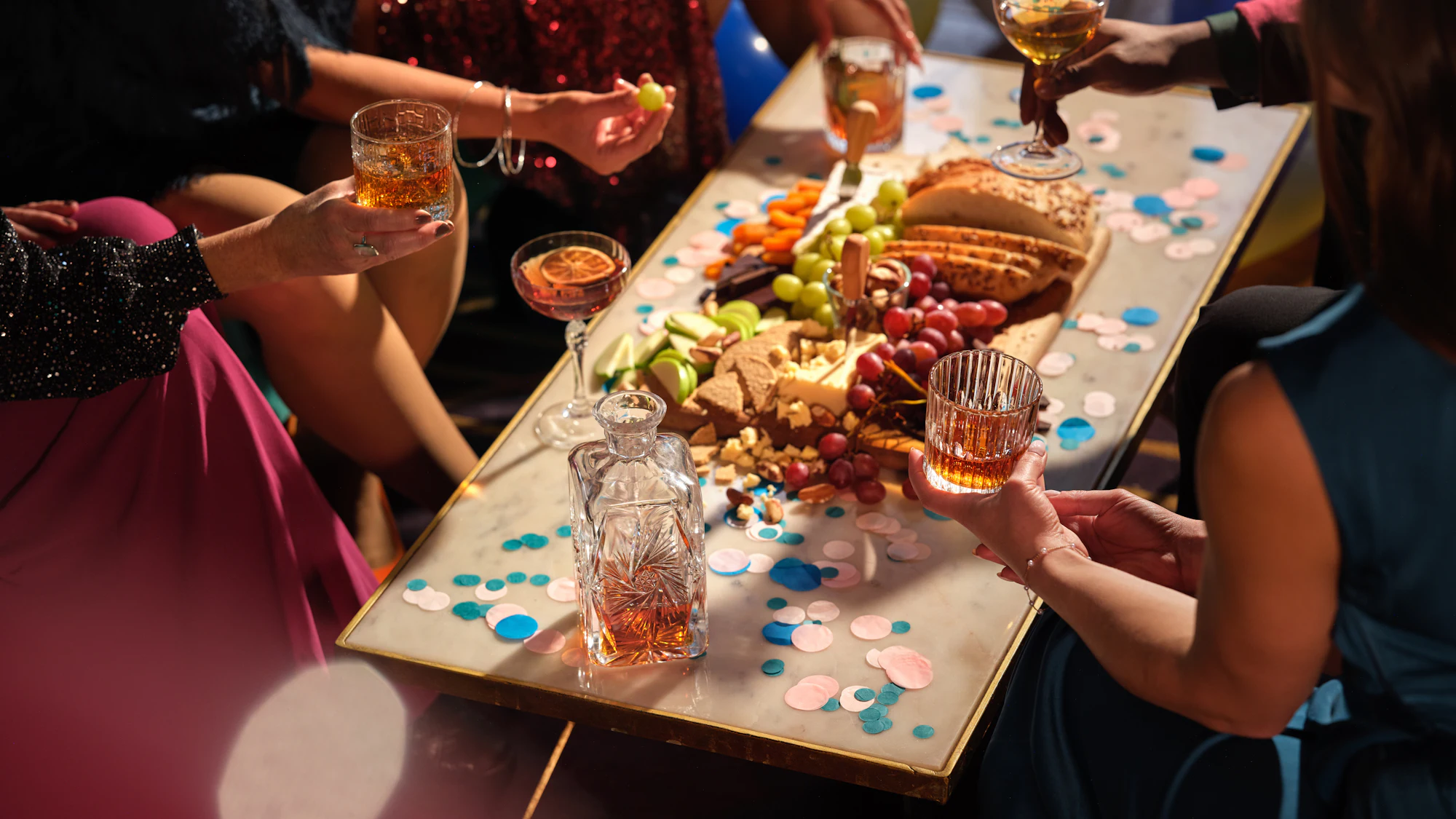 Friends sharing drinks and confetti at a sparkling Christmas party table