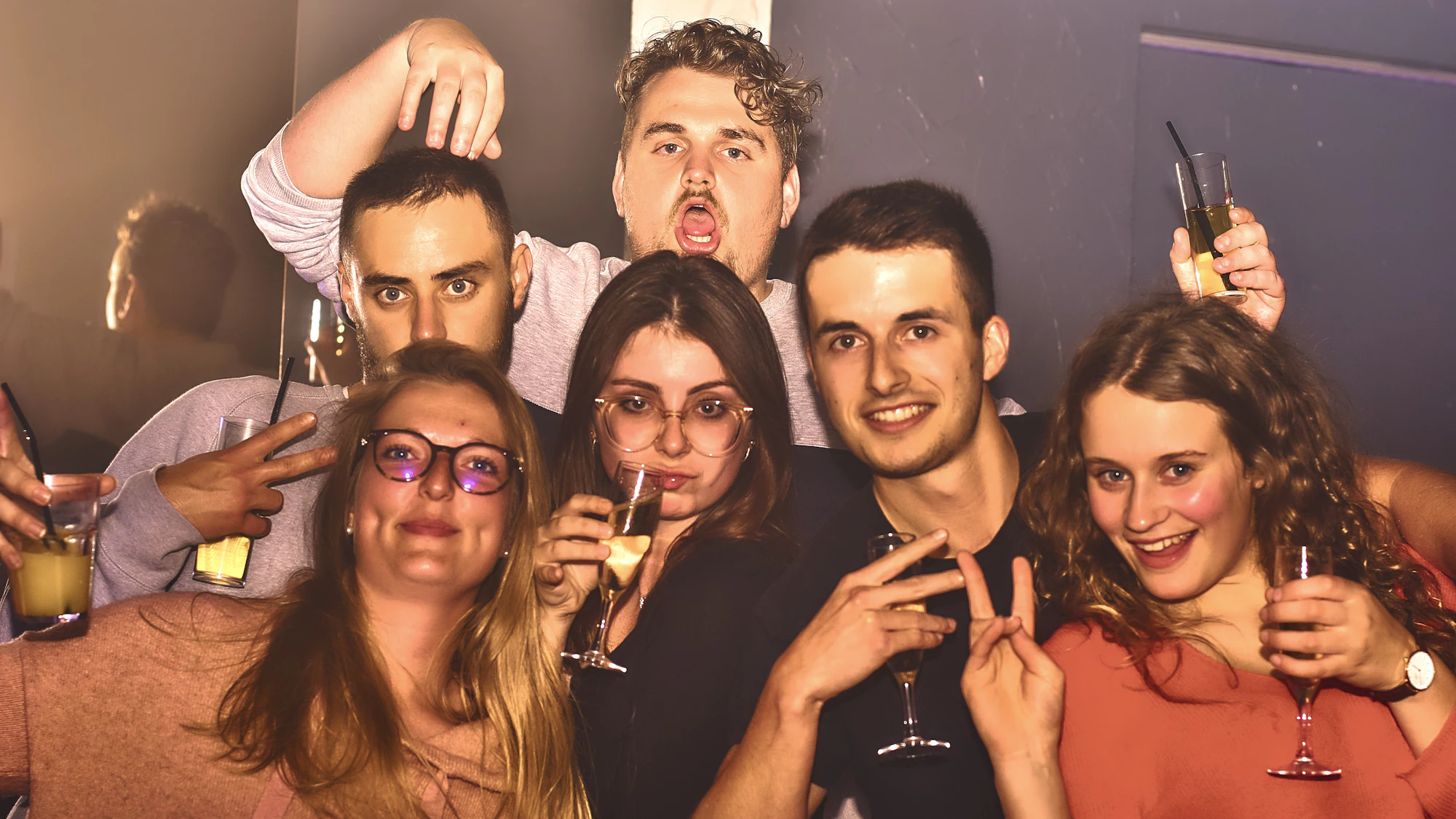 Group of friends striking playful poses for a flash-lit party photo