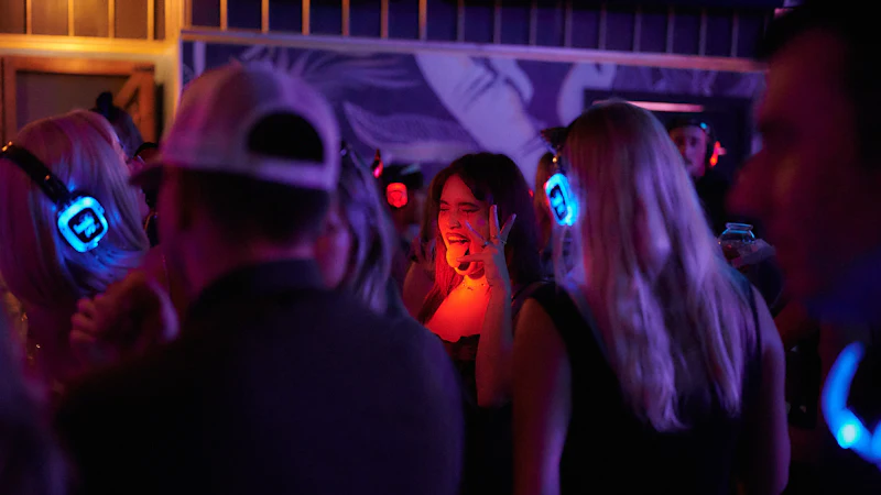 Friends laughing in glowing headphones at a silent disco night